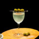 Dirty Martini mit aufgespießten grünen Oliven